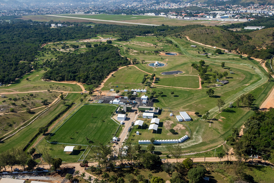 Vista aérea próxima do Centro Olímpico de Hipismo em Deodoro, mostrando arenas, pistas, baias e o entorno verde da floresta.
