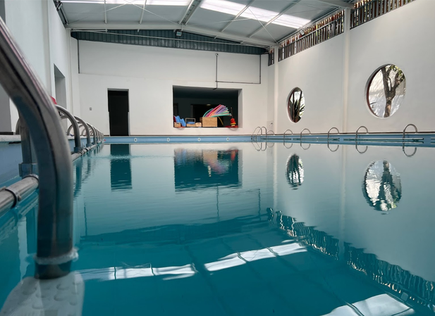 Piscina pedagógica coberta, com janelas circulares e a portinha aberta para a área de apoio.