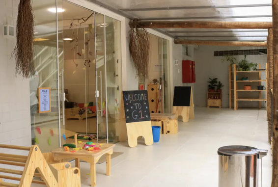 Sala de aula em pedagogia Reggio Emilia, com móveis baixos de madeira, lousas e materiais didáticos dispostos ao alcance das crianças.
